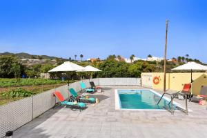 a swimming pool with chairs and umbrellas on a patio at Los Algodones Cottage with Pool in Ingenio