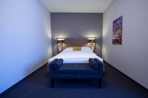 a bedroom with a bed and a blue chair at V Boutique Hotel Böblingen in Böblingen