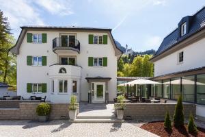 a large white house with green shutters at Hotel Villa Ludwig in Hohenschwangau
