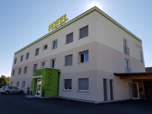 a white building with a green door in a parking lot at Hotel Rimo in Ort im Innkreis