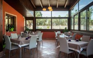 a dining room with tables and chairs and windows at Feudo delle Querce in Vena