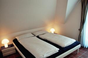 a bedroom with a bed with two lamps on it at Appartement Kayser Sylt in Morsum