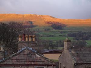 a view of a house with a hill in the background at Herriot's in Hawes