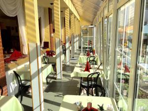 a restaurant with white tables and chairs and windows at Hotel Rodebachmühle in Georgenthal