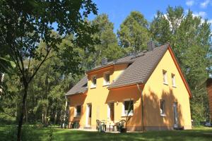 una casa amarilla con techo negro en Haus Ostseekueste en Ostseebad Karlshagen
