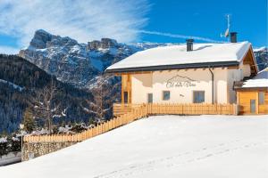 un edificio ricoperto di neve con montagne sullo sfondo di Col Dala Vara a San Cassiano