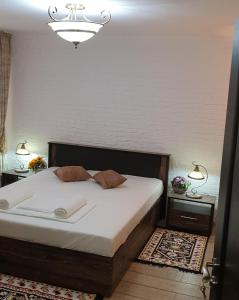 een slaapkamer met een bed met witte lakens en een kroonluchter bij Garsoniera 1 decembrie in Alba Iulia