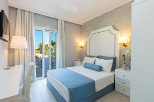 1 dormitorio con cama azul y balcón en Georgioupolis Plaza Suites en Georgioupolis