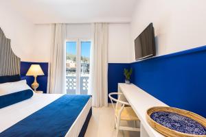 niebiesko-biała sypialnia z łóżkiem i telewizorem w obiekcie Georgioupolis Plaza Suites w mieście Georgioupolis