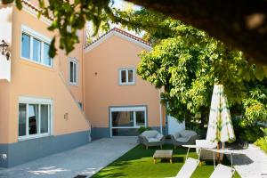 a house with chairs and an umbrella in a yard at Duques Villa Luxury Guesthouse in Lisbon
