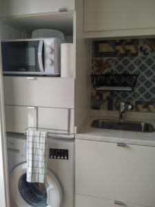 a kitchen with a washing machine and a microwave at Casa da Tia Adozinda in Lisbon