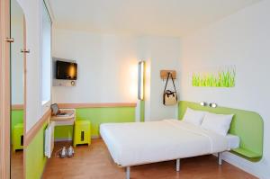 a hotel room with a bed and a tv at ibis budget Saint Dié des Vosges in Saint Die