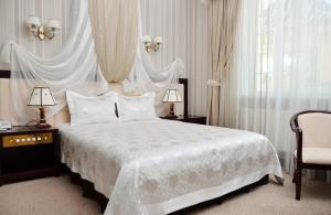 a bedroom with a white bed with two lamps and a chair at Sofievsky Posad Hotel in Kyiv