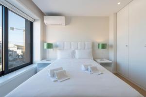 ポルトにあるLovelyStay - Trindade Cozy Apartmentの白いベッドルーム(大きな白いベッド1台、窓付)