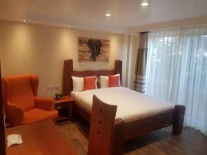 a hotel room with a bed and a chair at Progressive Park Hotel in Nairobi