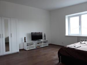 a white room with a television on a white cabinet at Tilžės gatvė 144 in Šiauliai