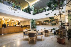 a restaurant with tables and chairs and plants at Zenit Wellness Hotel Balaton in Vonyarcvashegy
