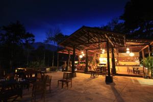 a patio with tables and chairs at night at Rock and Tree House Resort in Khao Sok