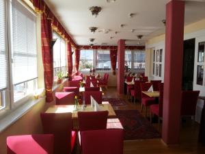 un restaurante con sillas rojas, mesas y ventanas en Liezenerhof, en Liezen