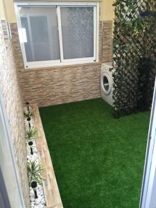 einen kleinen Hinterhof mit grünem Gras und einem Fenster in der Unterkunft Piso en O Grove in O Grove