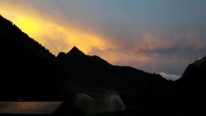 - un coucher de soleil sur une chaîne de montagnes avec une cascade dans l'établissement Haus St. Michael 2, à Binn