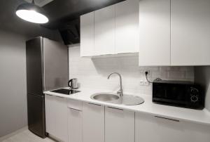 eine weiße Küche mit einer Spüle und einem Kühlschrank in der Unterkunft MyAparts R2 in Lwiw