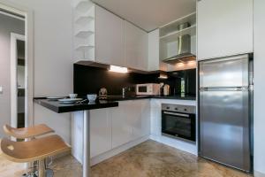 kuchnia z białymi szafkami i lodówką ze stali nierdzewnej w obiekcie Costa Del Sol Beach Apartment w mieście Estepona