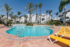 basen z krzesłami i palmami w ośrodku w obiekcie Costa Del Sol Beach Apartment w mieście Estepona