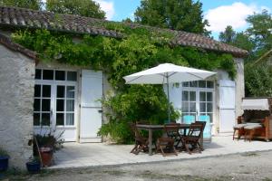 einen Tisch mit einem Sonnenschirm außerhalb eines Hauses in der Unterkunft l'Ecurie - La Maïsou in Sérignac