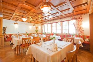 un restaurante con mesas y sillas blancas y ventanas en Hotel Gasthof Engel, en Appenweier