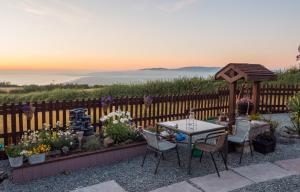 a patio with a table and chairs and flowers at Enlli Fach pet friendly Cabin , sleeps 2 adults 2 children not suitable for contract workers due to parking in Borth