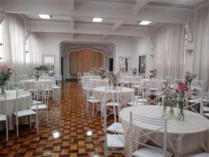 um salão de banquetes com mesas brancas, cadeiras e flores em Aurora Hotel em Ribeirão Preto