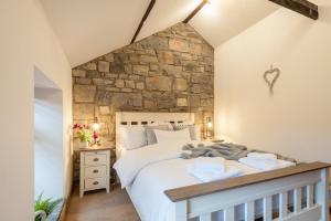a bedroom with a large bed and a stone wall at Bryn-Y-Groes Cottage in Ystradgynlais
