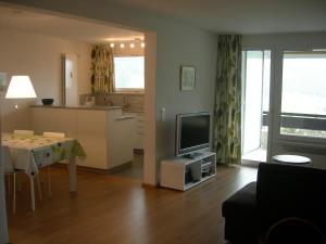 ein Wohnzimmer mit einem Tisch und einem TV sowie eine Küche in der Unterkunft Apartment Alpenblick Superior in Davos