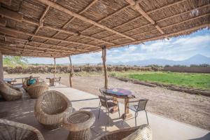 a patio with chairs and tables and a view of a field at Planeta Atacama Lodge in San Pedro de Atacama