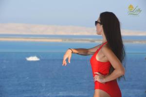 Una mujer con un vestido rojo de pie en la playa en Lilly Apartments, en Hurghada