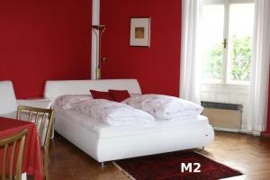 a bedroom with a white bed in a red wall at Seeappartements Excelsior in Velden am Wörthersee
