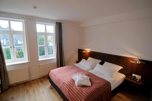 a bedroom with a bed with a red blanket and two windows at Hotel Am Burgmannshof in Wunstorf