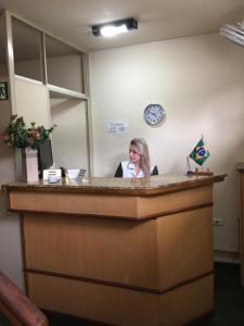 a woman is sitting at a reception desk at Podium Hotel in São Caetano do Sul
