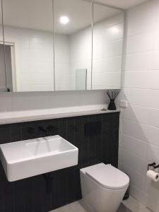 a bathroom with a sink and a toilet and a mirror at Modern & Cozy Unit Just Steps from Terrigal Beach in Terrigal
