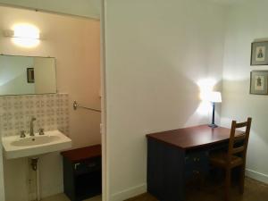 a bathroom with a sink and a desk with a lamp at La grande maison de Carrouges in Carrouges
