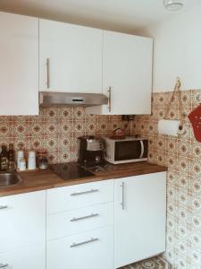 a kitchen with white cabinets and a microwave at Dabbanna in Chiaramonte Gulfi