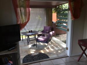 eine Terrasse mit 2 Stühlen, einem Tisch und einem TV in der Unterkunft Mediteranean style Ohana Rental / Garden Bungalow in Pahoa in Honolulu Landing