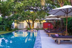a pool with lounge chairs and umbrellas next to a resort at Pippali Boutique Hotel in Kampot