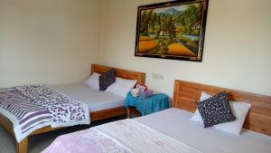 - une chambre avec 2 lits et une photo sur le mur dans l'établissement Kabera House 2, à Ubud
