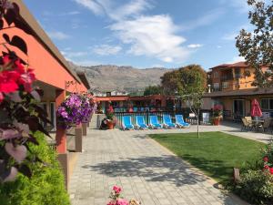 a resort with chairs and tables and mountains in the background at Sahara Courtyard Inn & Suites Osoyoos in Osoyoos