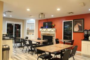 a room with tables and chairs and a fireplace at Hawthorn Suites Wichita East in Wichita