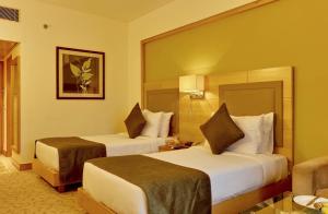 una camera d'albergo con due letti e una sedia di The Suryaa New Delhi a Nuova Delhi