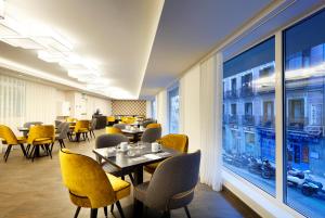 restauracja ze stołami i krzesłami oraz dużym oknem w obiekcie Eurostars Madrid Gran Vía w Madrycie