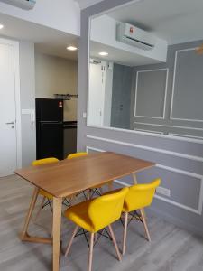 吉隆坡的住宿－Robertson by MiRic，一间带木桌和黄色椅子的用餐室